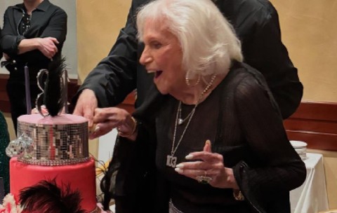 Carole Roth suflă în lumânările de pe tortul pe care l-a primit când a făcut 103 ani