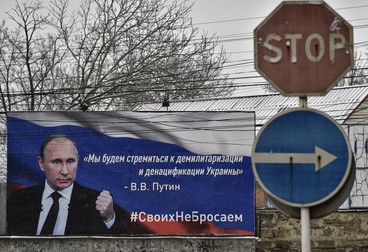 Un afiș cu o poză a președintelui rus Vladimir Putin și sloganuri pe care scrie „Vom lupta pentru demilitarizarea și denazificarea Ucrainei” pe o stradă din Simferopol, Crimeea, 10 martie 2022. Foto: EPA