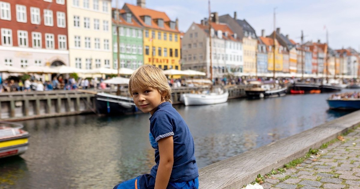 Un copil stă in zona canalului Nyhavn, din Danemarca, in timpul vacanței.
