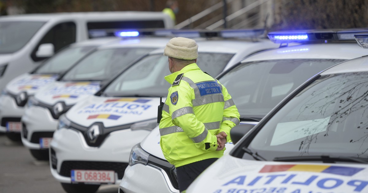Un polițist stă cu mâinile la spate lângă mașini de la Poliția Locală.