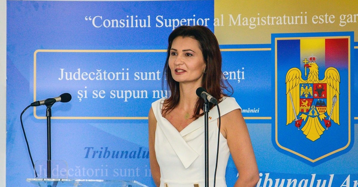 O judecatoare imbracata in alb vorbeste la un microfon