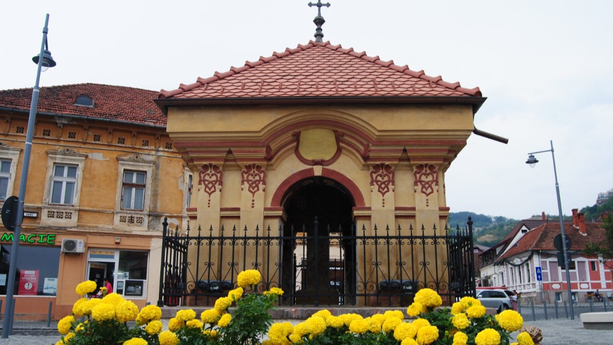 O troiță din Brașov, are pereții vopsiți galben și modelele sunt desenate cu vișiniu, acoperișul este din țiglă portocalie