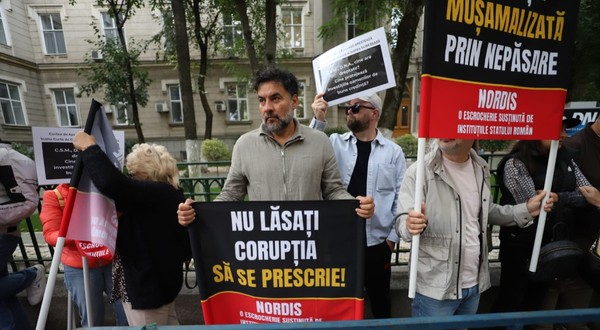 Mai mulți protestatari care țin bannere și pancarte cu mesaje împotriva corupției în fața DNA