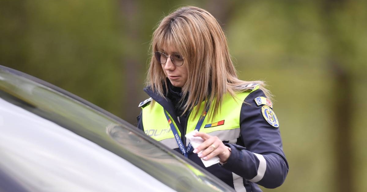 femeie politist imbracata in uniforma, in dreptul unei masini oprite, posibil sa ceara documentele de identificare