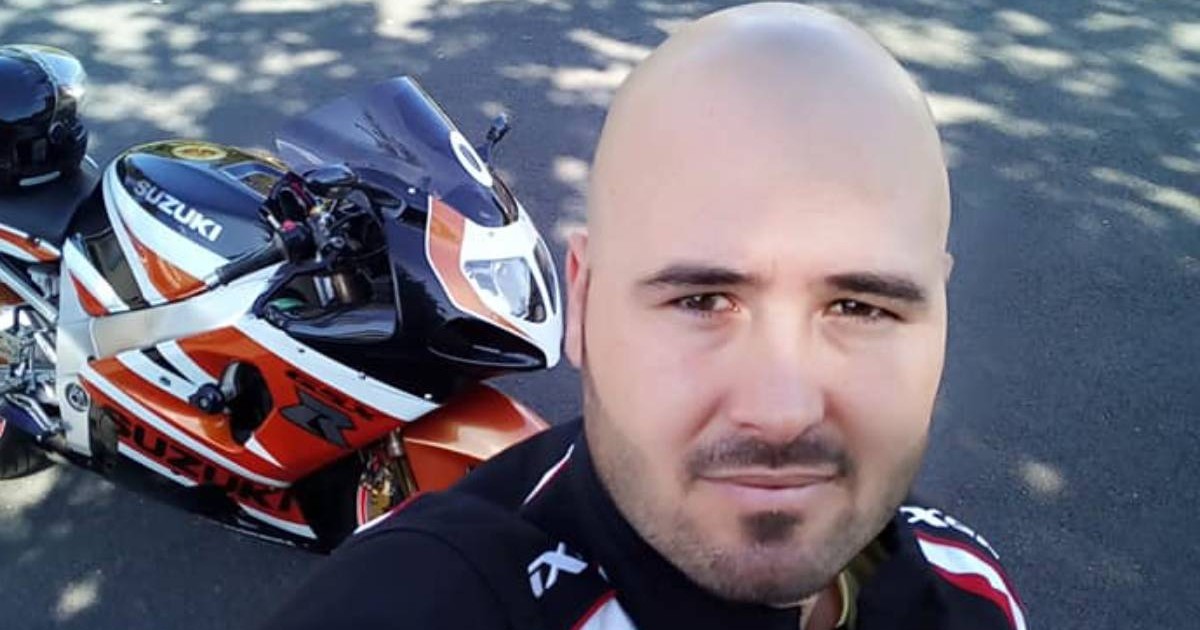 Alin Stroe, roman stabilit in Franta, cadru strans, in costum de motociclist negru cu alb si rosu, in spate se vete motocicleta Suzuki in acealeasi culor