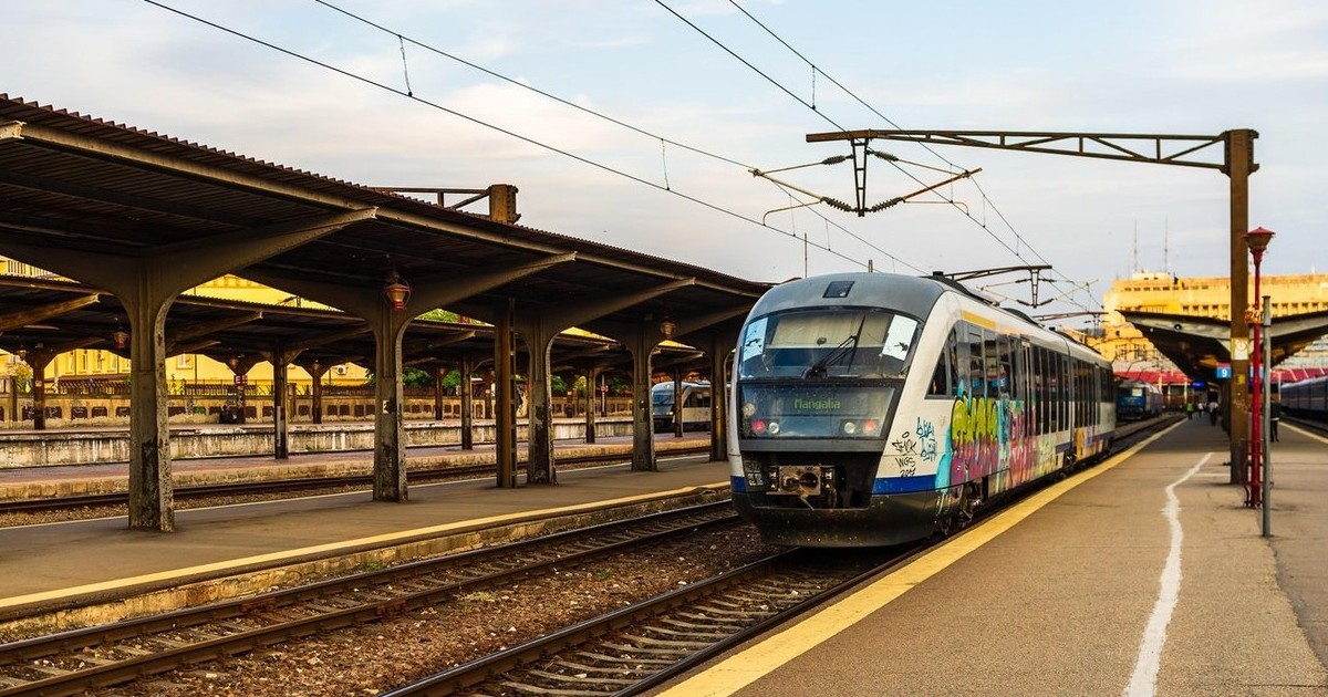 Un tren stă în stație într-o gară, iar peronul este gol