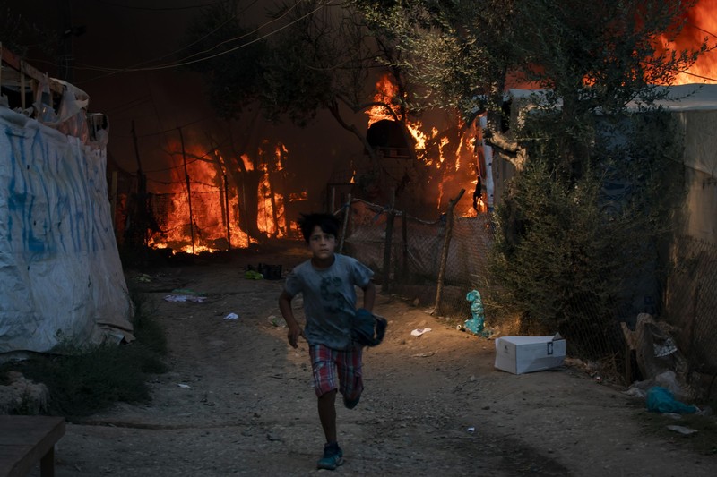 Copil fugind din calea incendiului care a cuprins tabăra Moria pe 8 septembrie | Foto: Hepta