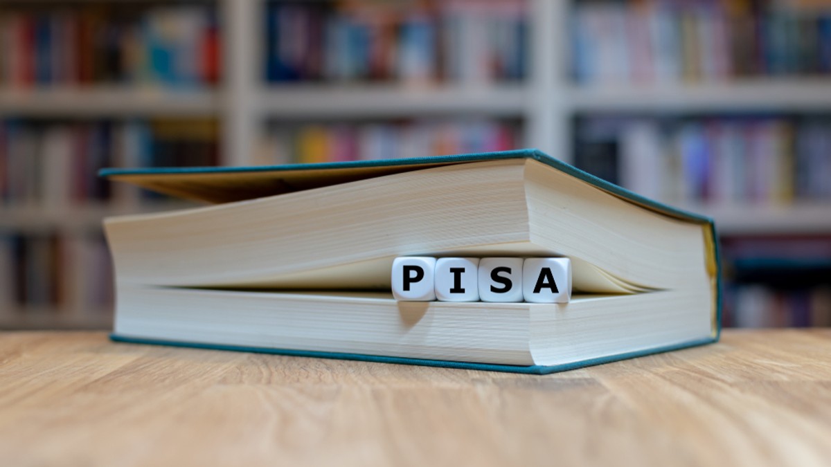 Ce sunt testele Pisa. Modele de teste Pisa - Imagine reprezentând cuvântul PISA, format din cuburi cu câte o literă, aşezat între paginile unei cărţi