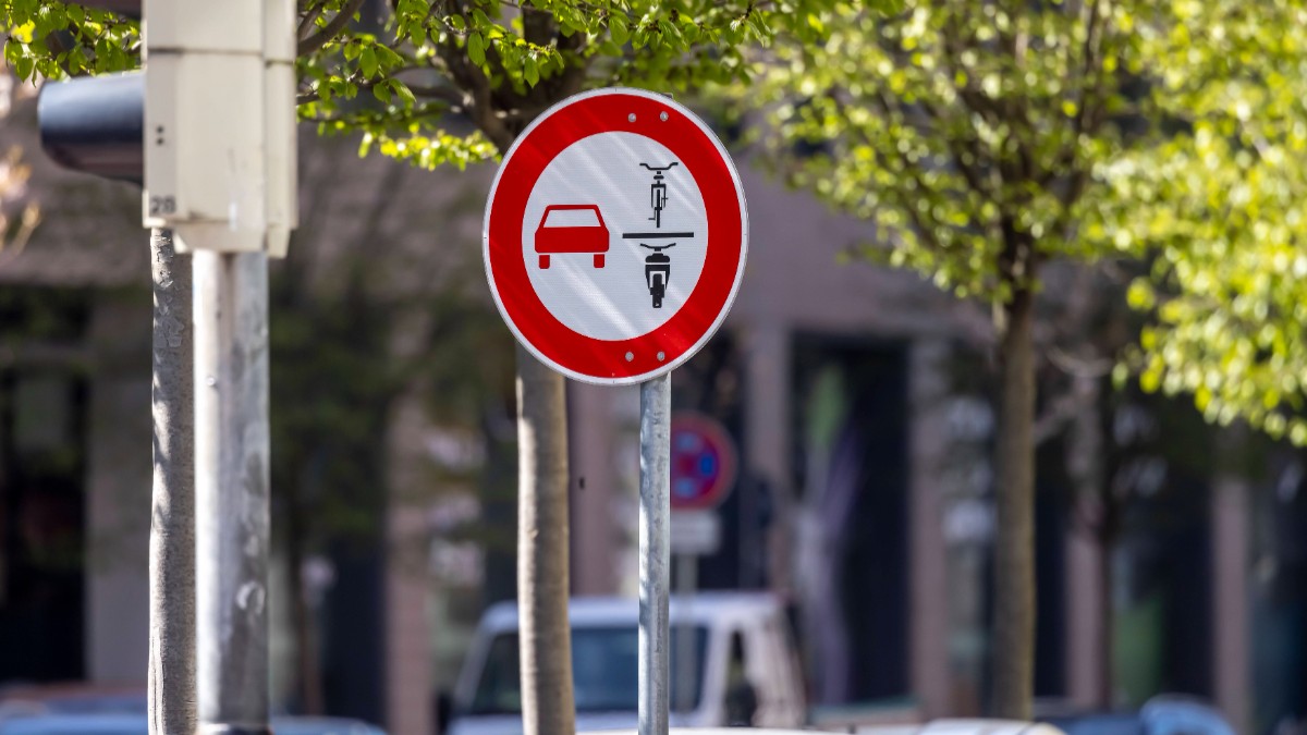 Un indicator în formă de cerc roșu, în care este o mașină roșie în partea stângă, o bicicletă și o motocicletă neagră, în dreapta.