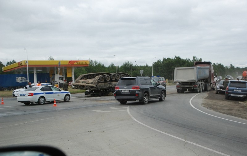 Un tanc de luptă al armatei ruse, cu șenilele în sus, pe șosea, răsturnat într-o curbă