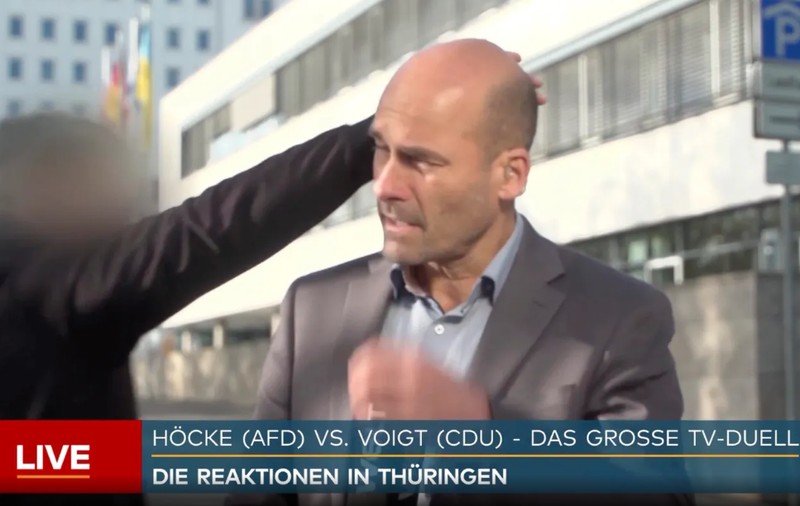 Momentul în care un reporter german primește o palmă peste ceafă și un bobârnac, în timp ce transmitea în direct | VIDEO