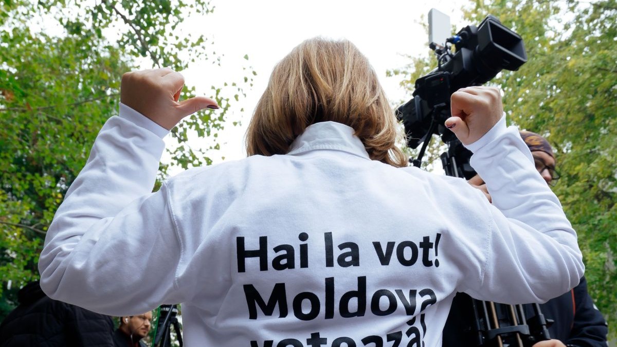 O femeie stă cu spatele și arată mesajul scris pe tricou: „Hai la vot! Moldova votează”, octombrie 2024