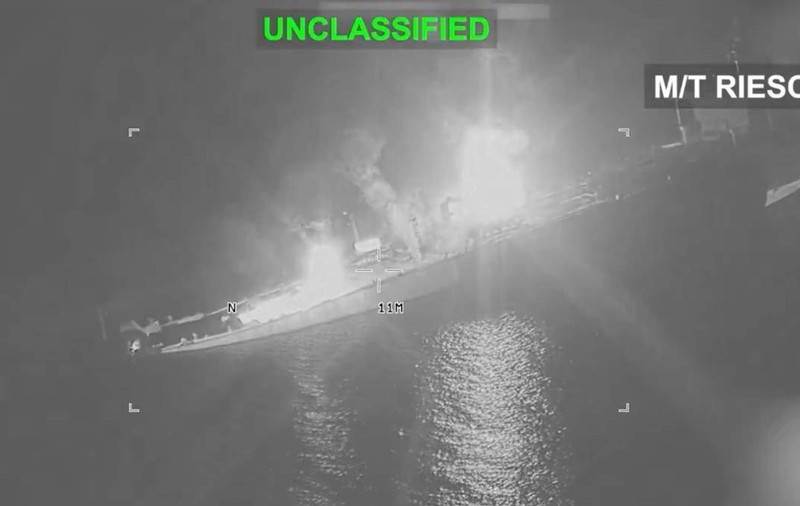 Imagine nocturnă, surprinsă în infraroșu, cu un petrolier cuprins de flăcări pe mare. Focul și fumul sunt vizibile în zona centrală a navei, iar pe cadru apar marcajele „UNCLASSIFIED” și „M/T RIESCO”.