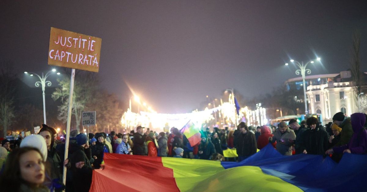 În fața unui trocolor românesc, mai mulți tineri protestează