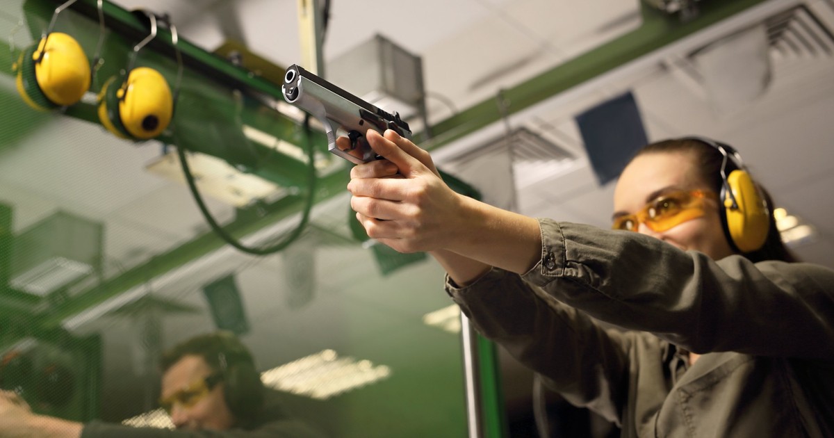 Unde poți trage cu arma în București - O tânără şi un bărbat trag cu pistolul într-un poligon de tir sportiv.