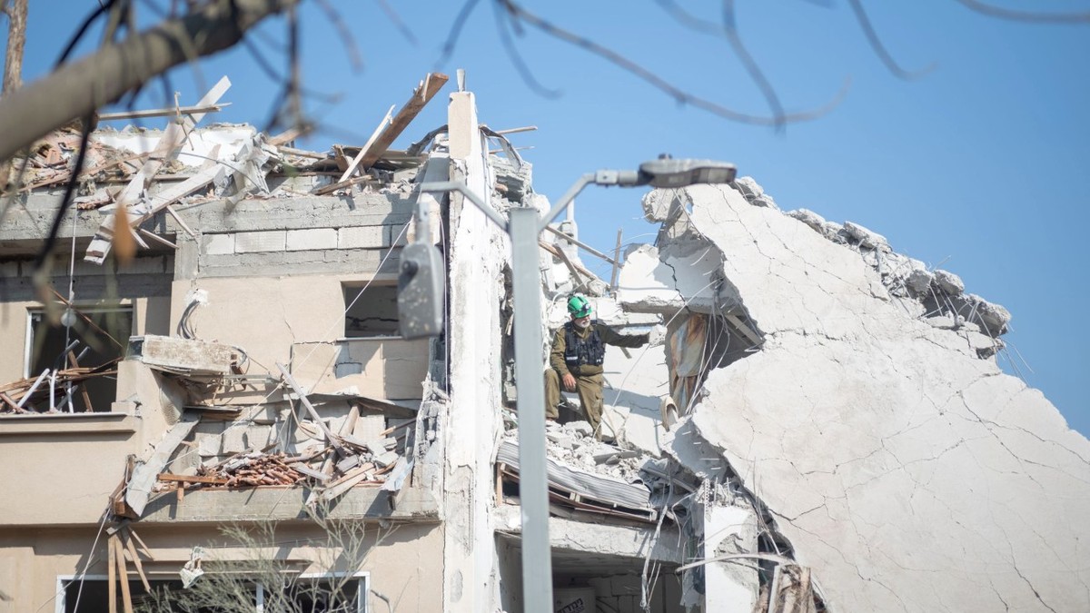 Muncitor israelian, cautand victime intr-o clădire distrusă după ce o rachetă iraniană a lovit o regiune din Israel