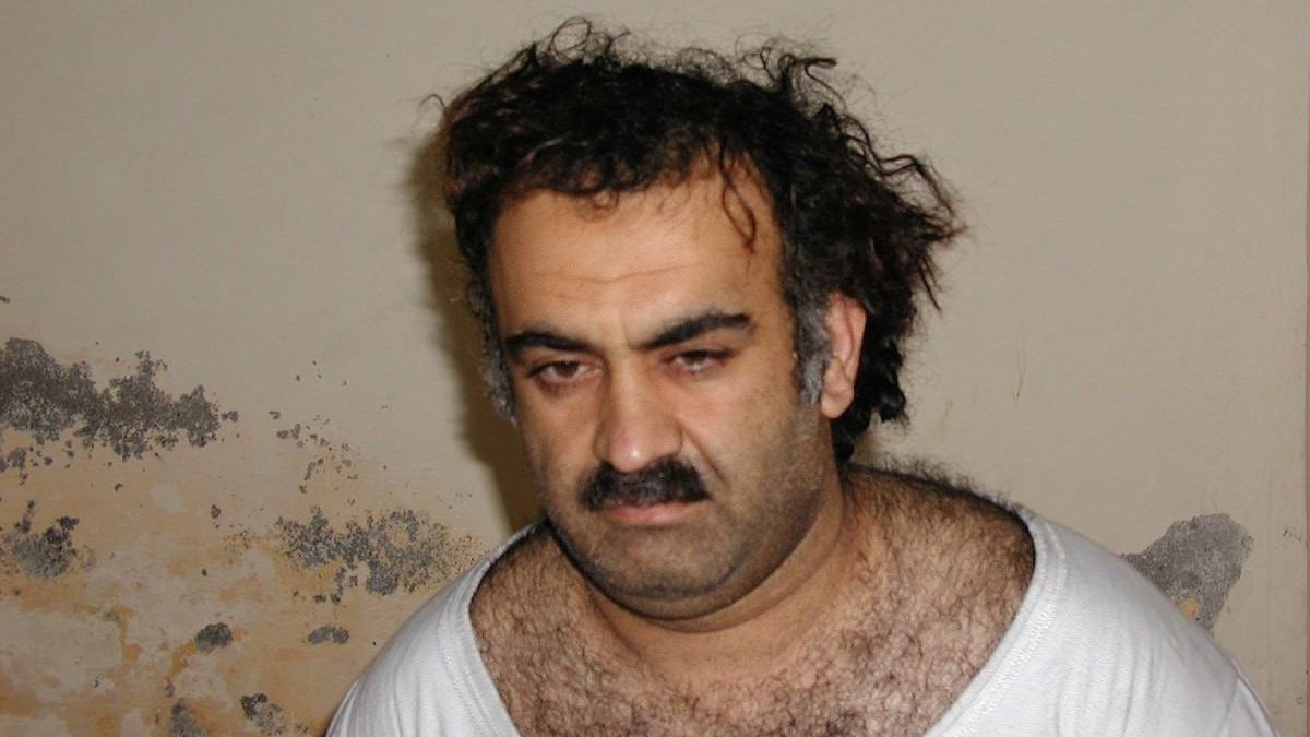 Khalid Sheikh Mohammed, creierul atacurilor din 11 septembrie 2001, îmbrăcat cu o bluză albă, și pe fundal un perete murdar