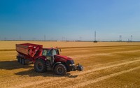 Un tractor roșu care a arat un lan de grâu și a strâns pe un câmp din România