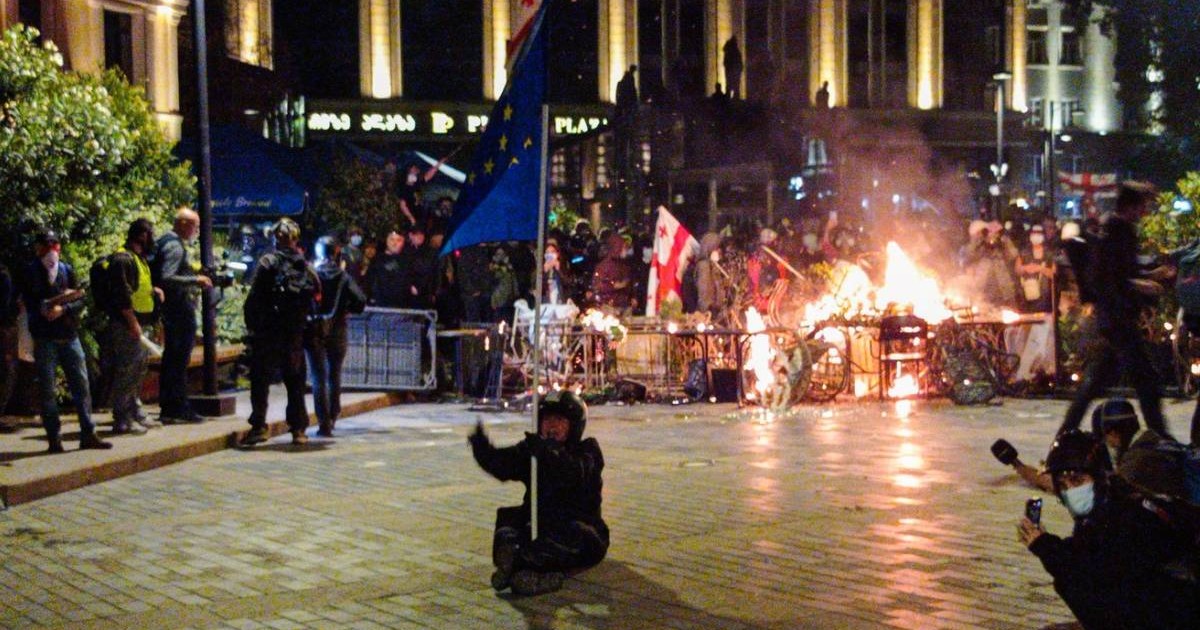 Protestatarii din Tbilisi izolați de polițiști, au dat foc unor piese de mobilier stradal, o persoană stă jos în mijlocul străzii cu un steag în mână