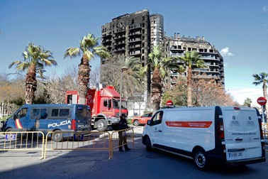 A police officer allows passage to a mortuary van at the multistorey residential block ravaged yesterday by a huge fire that killed at least four people, in Valencia on February 23, 2024. At least four people have died in a vast fire that ripped through a 14-storey apartment block in Valencia in eastern Spain, but officials warned today that the death toll could rise sharply. Fourteen people are still missing, the regional administrator said.,Image: 849858458, License: Rights-managed, Restrictions: , Model Release: no