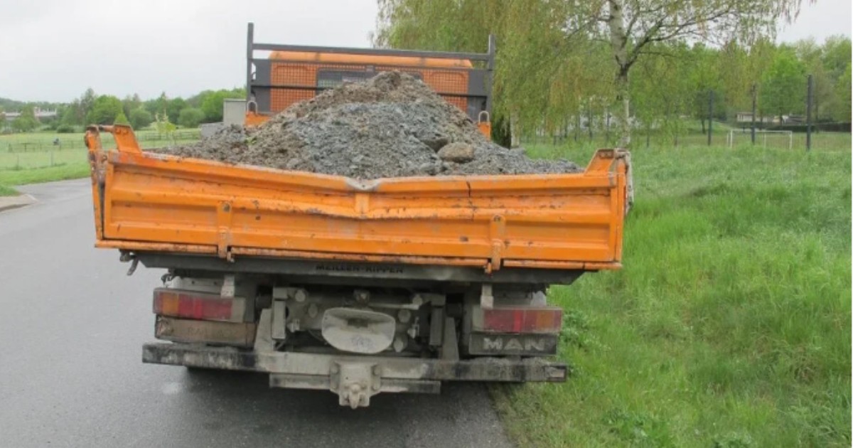 Un camion portocaliu aflat cu spatele, pe o șosea