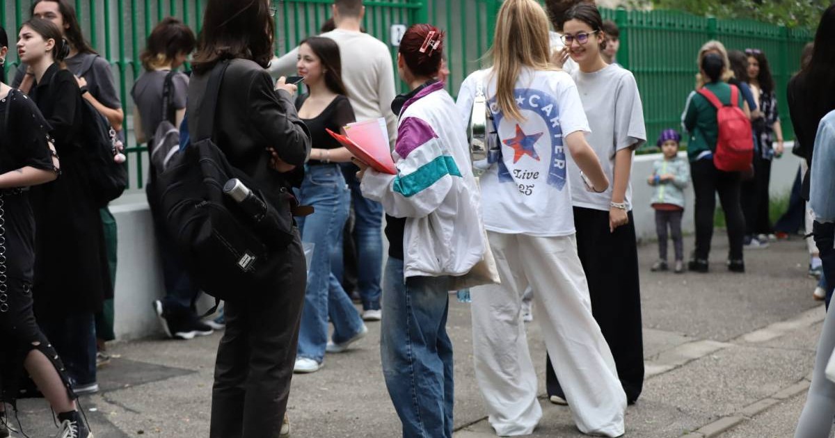 Un grup de elevi care discută despre subiectele la BAC 2025 stau pe trotuarul din fața Liceului Jean Monnet din București.