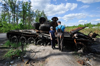 29 mai 2022. Un bărbat și un băiat se uită la un echipament militar rusesc distrus din satul Dmytrivka, lângă capitala Ucrainei Kiev. Foto: Profimedia