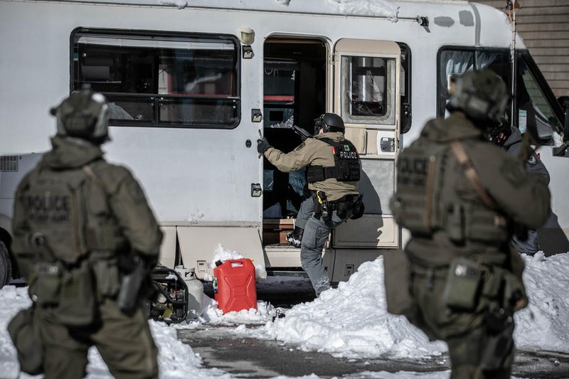 Polițiștii canadieni intră într-o rulotă parcată în centrul Ottawa pentru a aresta un protestatar | Foto: EPA