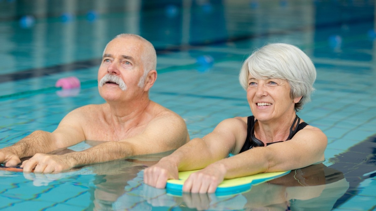 Exerciţii fizice potrivite pentru persoanele în vârstă- Un barbat si o femeie in varsta fac aerobic intr-o piscina acoperita