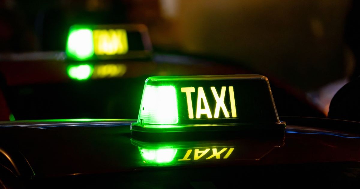 O mașină taxi din care se vede plafonul și care arată că este liberă pentru pasageri, fotografie făcută pe timp de noapte