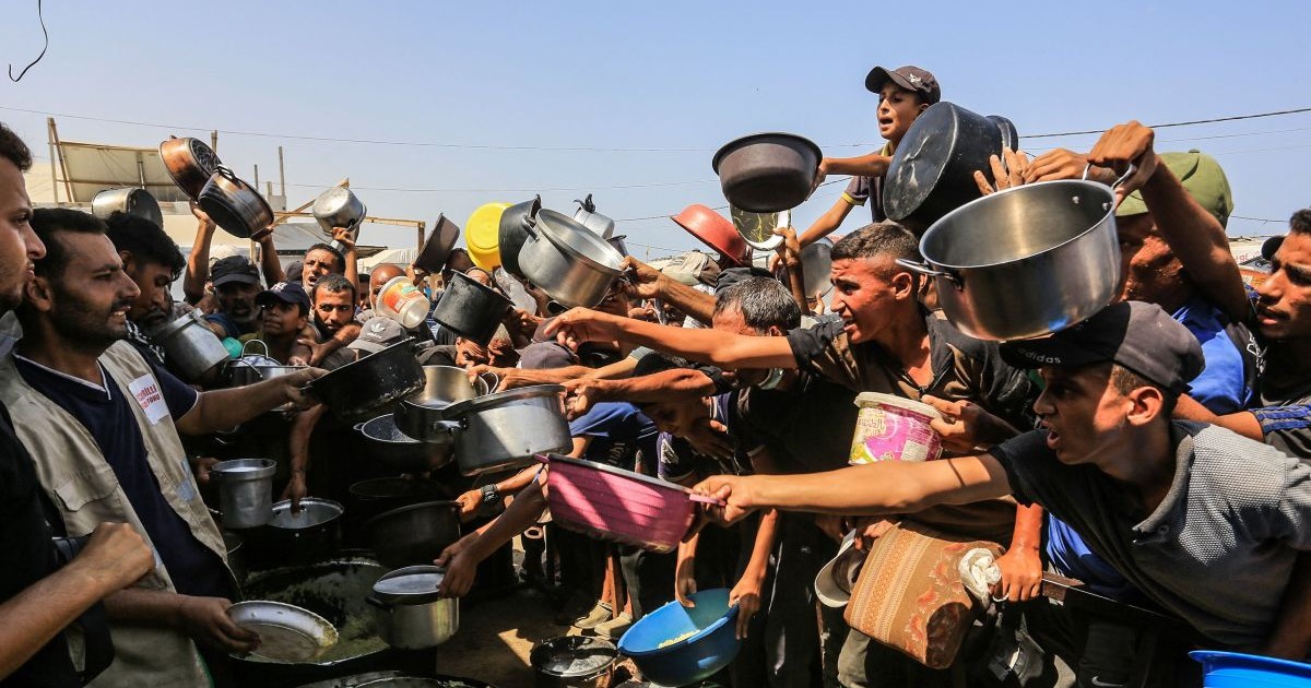 Palestinieni care se luptă cu foametea se adună în jurul unei organizații caritabile turcești care distribuie mâncare în zona Al-Mawasi din Khan Yunis, Gaza, august 2025