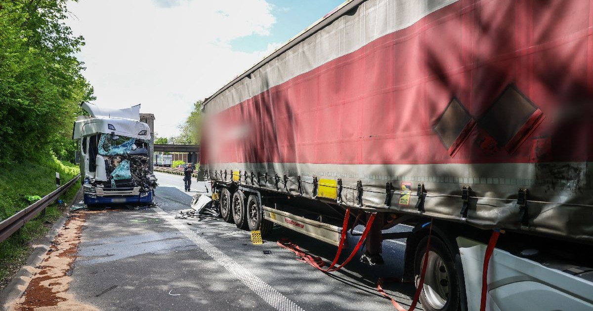 Un camion cu prelată roși și în spatele lui o cabină de camion complet distrusă