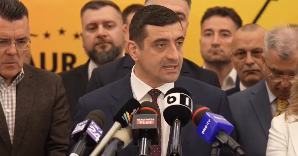 Un bărbat îmbrăcat la costum susține o declarație de presă în fața mai multor microfoane, fiind înconjurat de alți oameni. În spatele lui se vede un fundal galben, iar atmosfera sugerează un eveniment politic sau o conferință oficială.