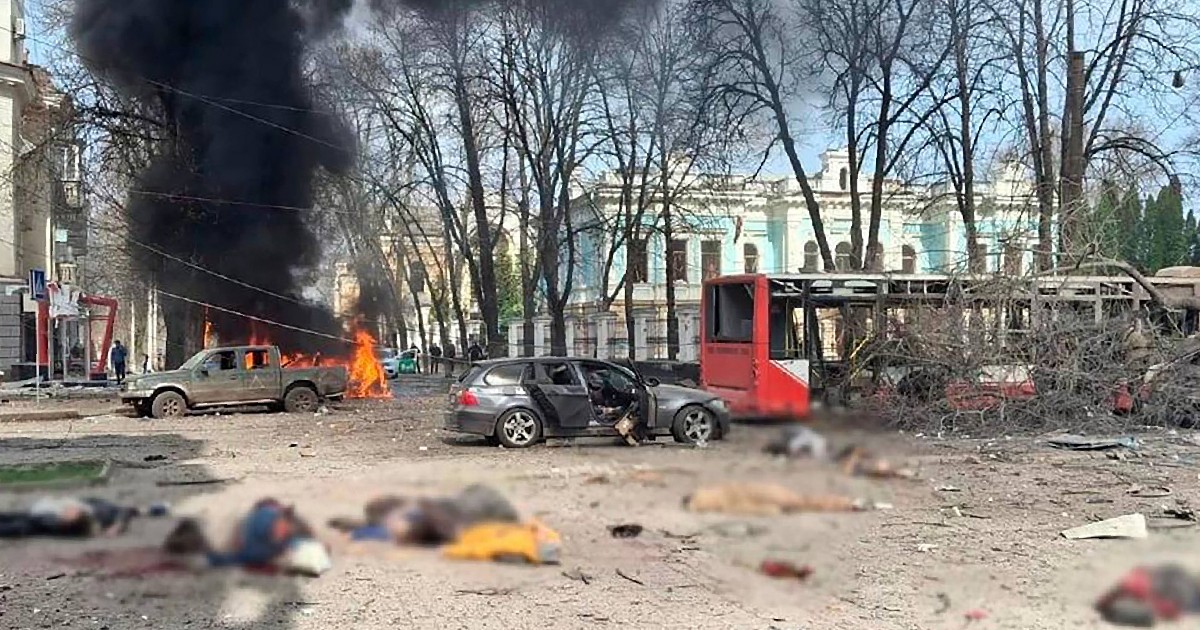 o mașină incendiată, un autobuz roșu și o mașină gri
