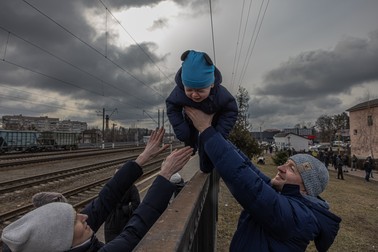 După ce a decis să rămână în Irpin, Ucraina, Oleg, (dreapta) îl trimite pe fiul său peste gard soției sale Yana, înainte de sosirea unui tren de evacuare către Kiev, pe 4 martie 2022.