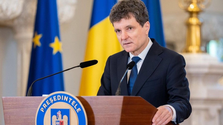 Imaginea îl prezintă pe Nicușor Dan vorbind de la o tribună oficială, având în fundal steagurile României și Uniunii Europene.