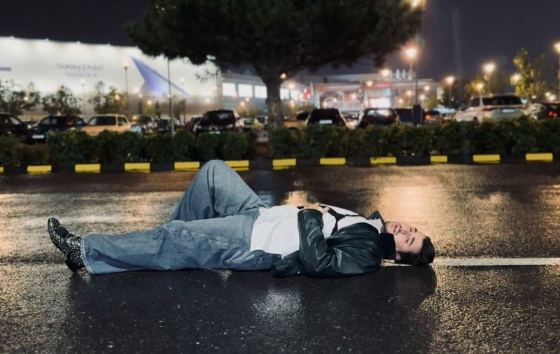 Cine este artistul filmat noaptea întins pe asfalt, în mijlocul ploii: „Scenă de film noir”
