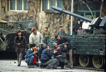Civili și soldați se ascund în spatele unui tanc de focuri și urmăresc lupte de la distanță. Foto: Profimedia