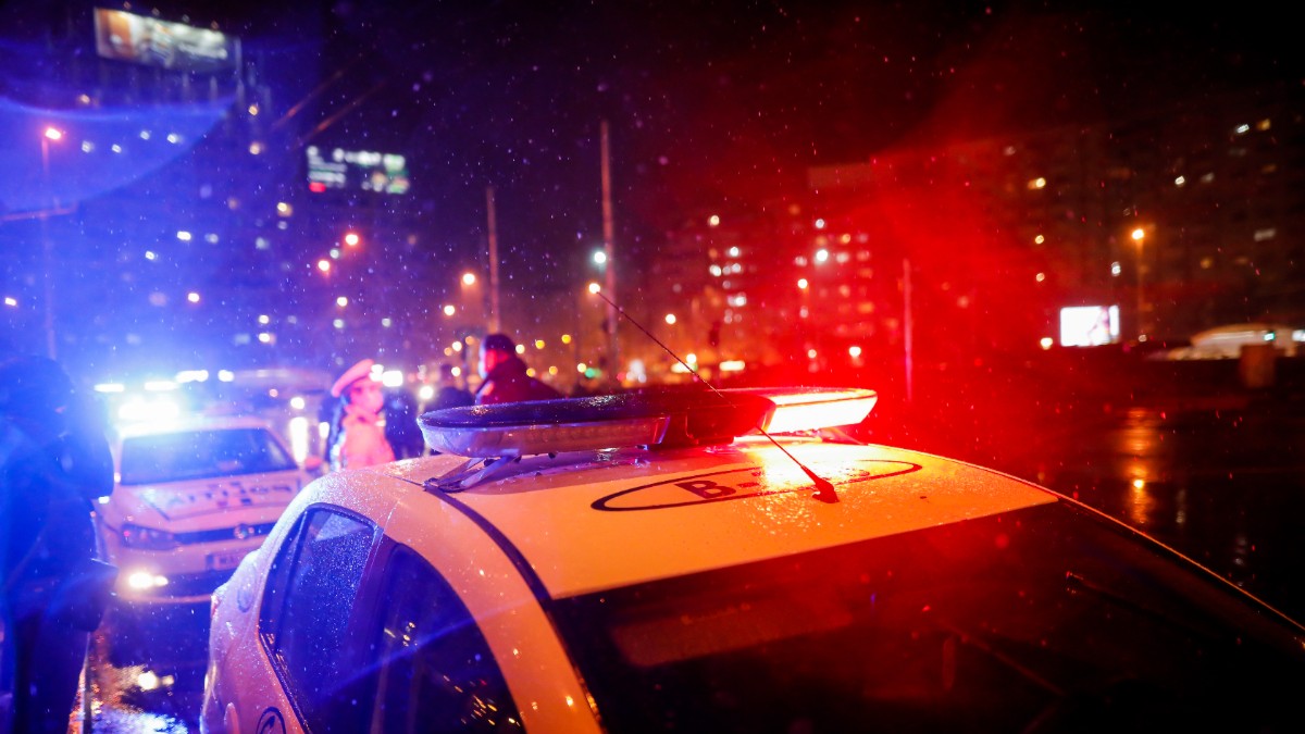 O mașină de poliție oprită pe un bulevard din București, doi polițiști stau și vorbesc în spatele lei