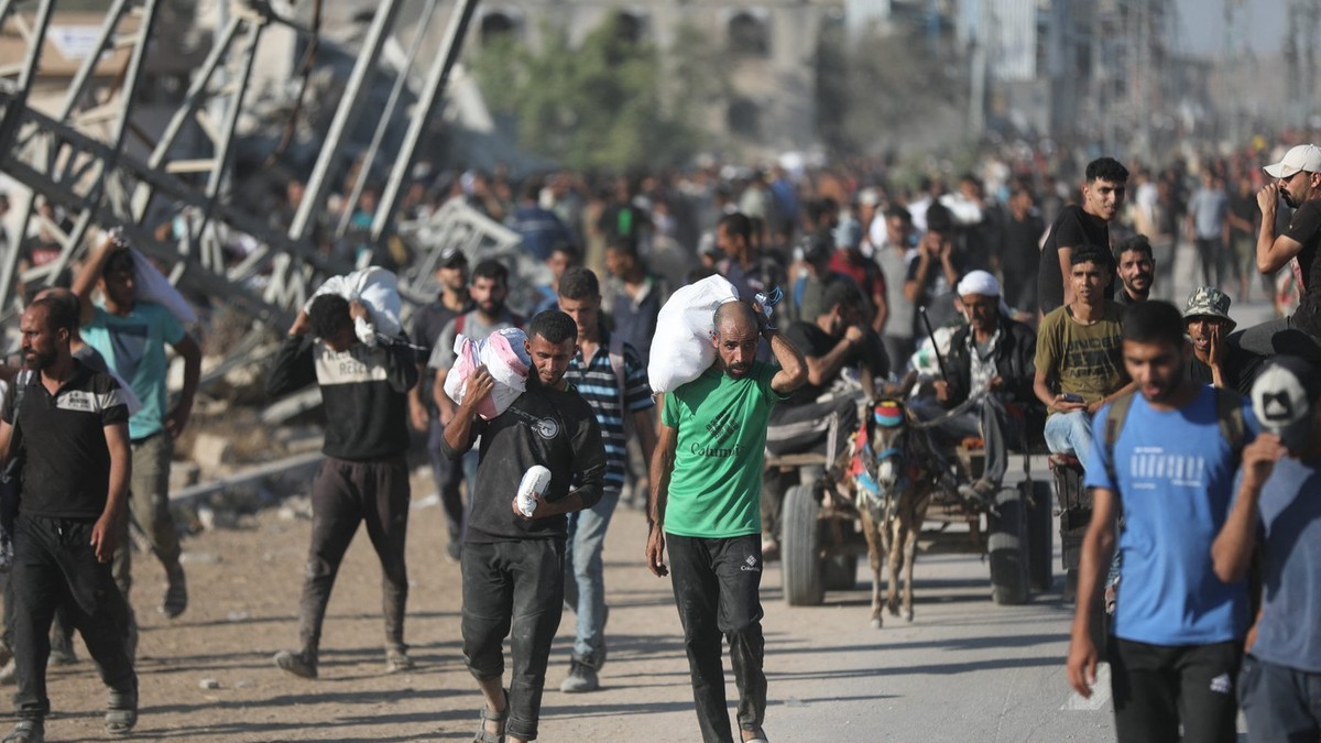 Palestinienii se întorc pe coridorul Netzarim cărând colete cu ajutoare primite de la un punct de distribuție al GHF Foto: Profimedia