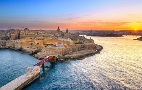 Imaginea prezintă o vedere aeriană asupra orașului istoric Valletta, capitala Maltei, văzută la apus de soare.