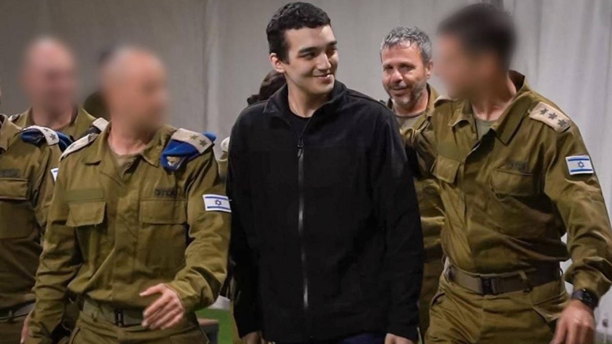 Tânărul israeliano-american, îmbrăcat sport, in hanorac si pantolon negre. încpnjurat de soldați în uniforme kaki eliberat de Hamas