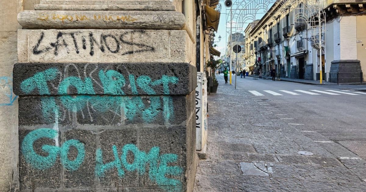 Un graffiti cu mesajul „turistule, pleacă acasă” pe colțul unei clădiri de pe o stradă din Catania, Sicilia, Italia.