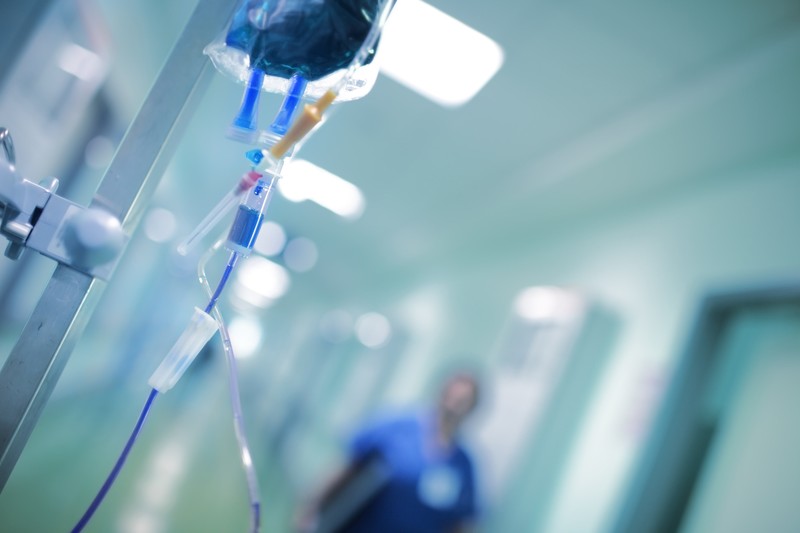 Intravenous drip with blue liquid ready to use on the background of walking around medical doctor, concept of mersy killing.