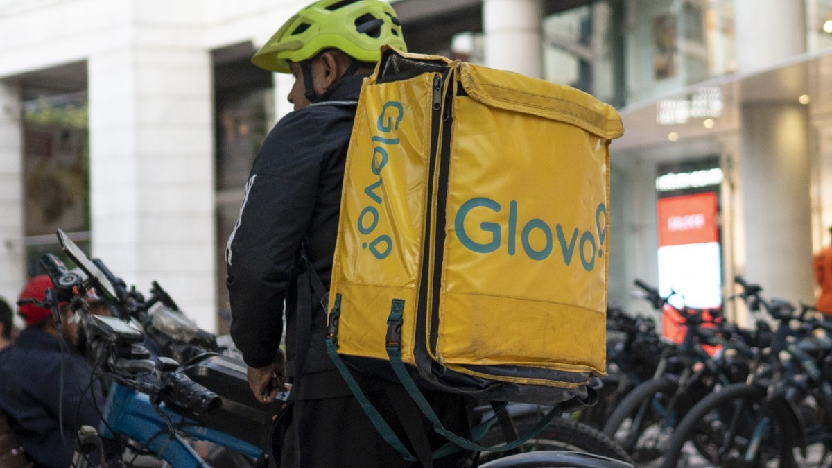 Un livrator cu rucsac Glovo, lângă mai multe biciclete