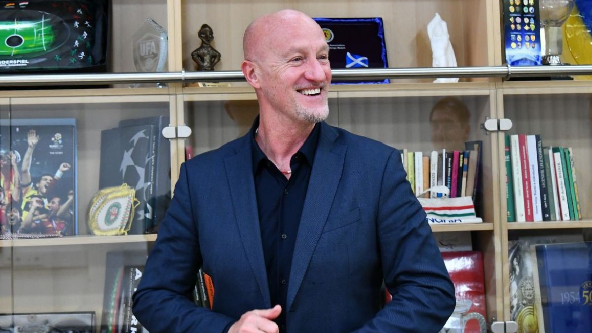 Marco Rosii zâmbește, pe fundal e o bibliotecă albă