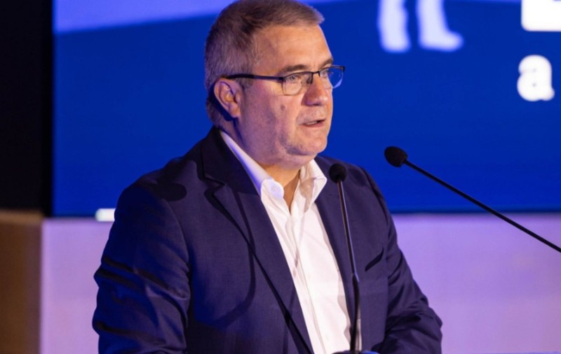  Sorin Gabriel Ionescu în costum albastru închis și cămașă albă, în timp ce vorbește la microfon