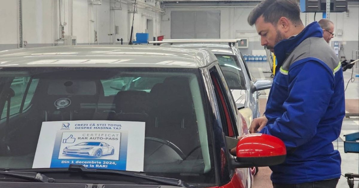 Inginer de la Registrul Auto Român (RAR), îmbrăcat în uniformă de culoare albastră, cu mânecă lungă, lângă o mașină roșie, care are un afiș în parbriz pe care sunt oferite informații despre certificatul RAR Auto-Pass