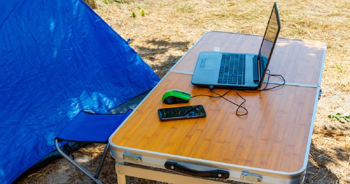 Gadgeturile care îți transformă rucsacul într-un birou complet - Imagine cu o masă de picnic pe care se află un telefon mobil, un laptop şi un mouse sugerând conceptul de nomad digital