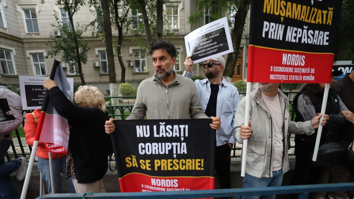 Mai mulți protestatari care țin bannere și pancarte cu mesaje împotriva corupției în fața DNA
